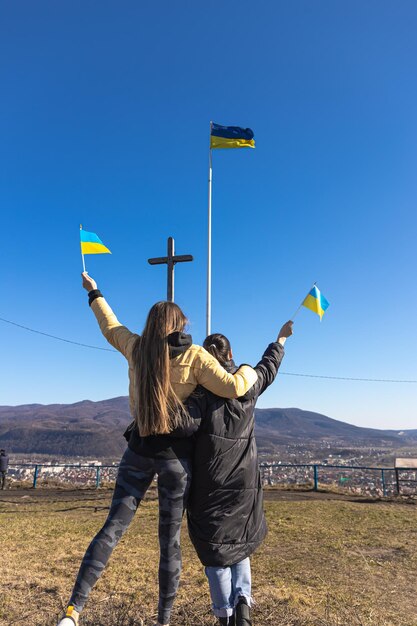 Frauen mit ukrainischen Flaggen vor dem Hintergrund des Himmels und der Berge