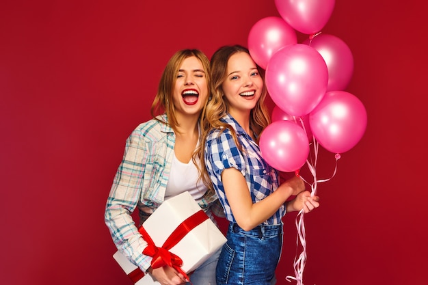 Frauen posieren mit großer Geschenkbox und rosa Luftballons