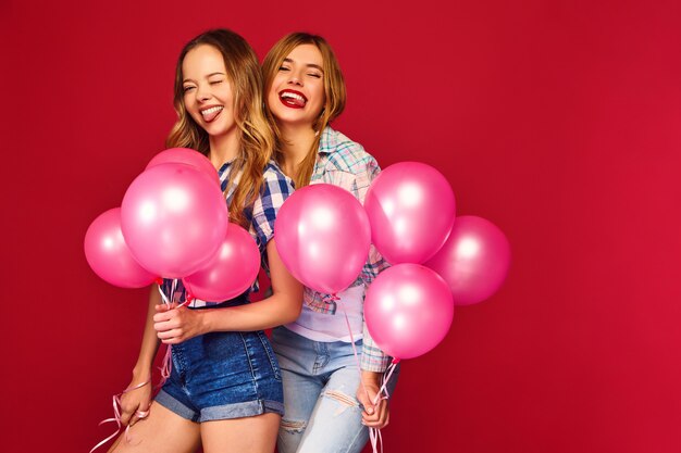 Frauen posieren mit großer Geschenkbox und rosa Luftballons