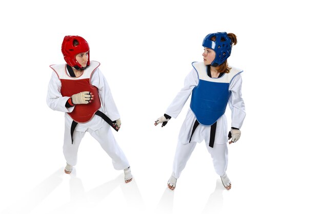 Frauen, professionelle Taekwondo-Athleten, die in spezieller Uniform auf weißem Hintergrund trainieren