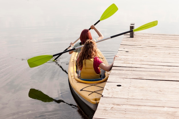 Kostenloses Foto frauen rudern kajak in der nähe von dock