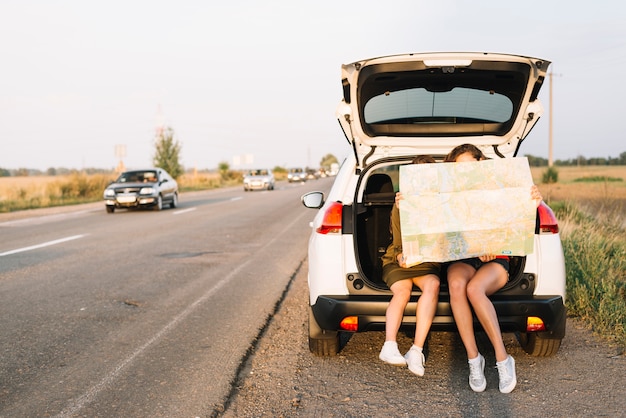 Frauen sitzen auf dem Auto mit Karte