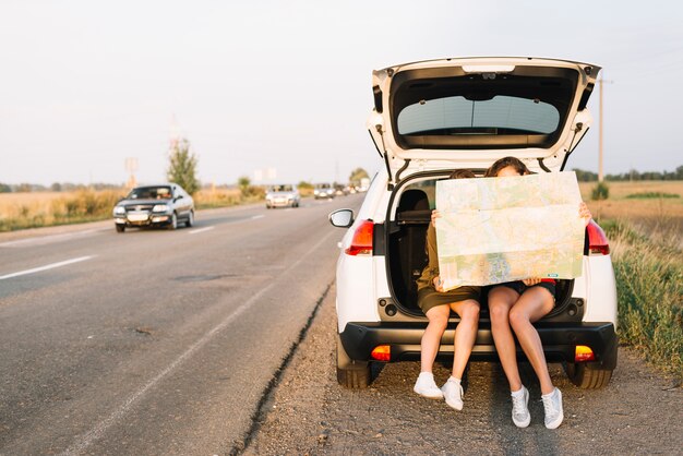 Frauen sitzen auf dem Auto mit Karte