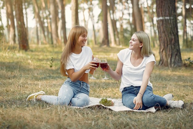 Frauen sitzen auf einem Picknick und trinken Wein