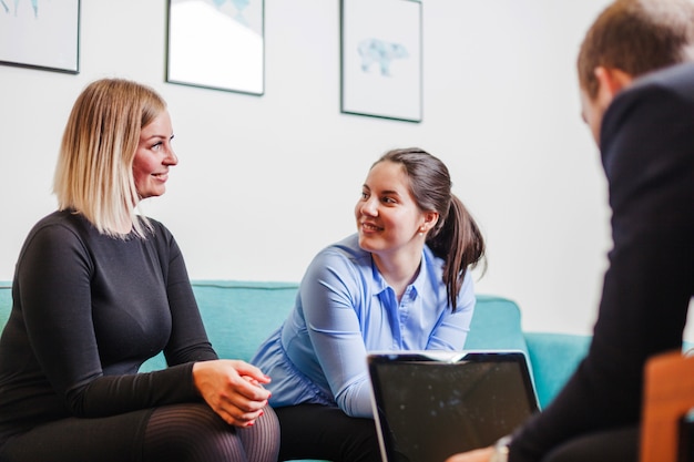 Frauen sitzen auf Sofa lächelnd