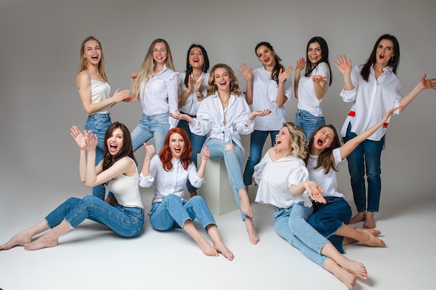 Frauen-Solidaritätskonzept. Stilvolles Personal des glücklichen jungen weiblichen Teams, das tragende Jeans posiert