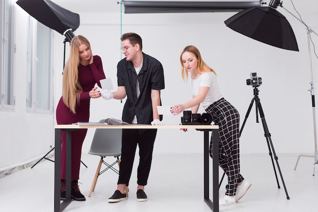 Frauen und Mann, die durch Fotos im Studio schauen