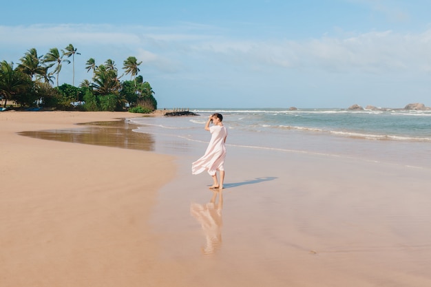 Frauenbeine, die auf dem Strandsand gehen