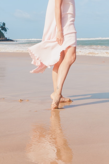 Frauenbeine, die auf dem Strandsand gehen