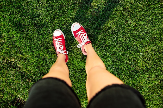 Frauenbeine, die auf Gras im Park stehen