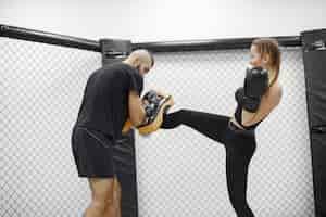 Kostenloses Foto frauenboxen. anfänger im fitnessstudio. dame in schwarzer sportbekleidung. frau mit trainer.