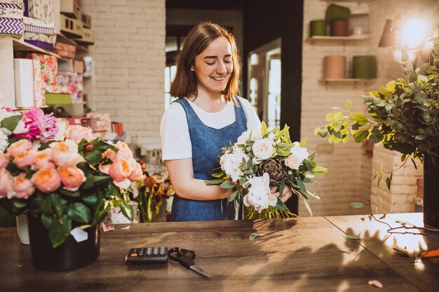 Frauenflorist an ihrem eigenen Blumenshop, der um Blumen sich kümmert