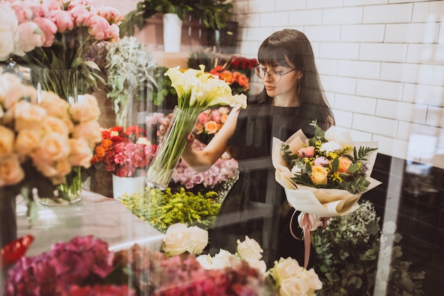 Frauenflorist an ihrem eigenen Blumenshop, der um Blumen sich kümmert