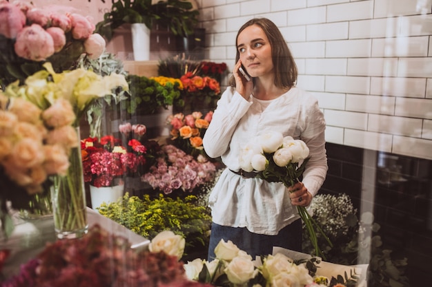 Frauenflorist an ihrem eigenen Blumenshop, der um Blumen sich kümmert