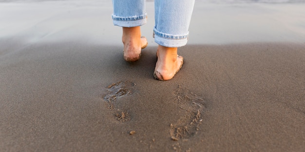 Kostenloses Foto frauenfüße auf dem sand am strand