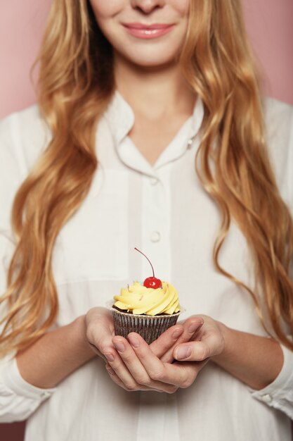 Frauenhände, die einen köstlichen leckeren kleinen Kuchen halten