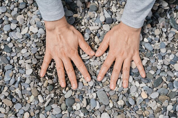 Frauenhände liegen auf den Meereskieseln Pebble Sea Beach Nahaufnahme dunkle runde Kieselsteine und graue trockene Kieselsteine Hochwertige Fotoidee für den Bildschirm