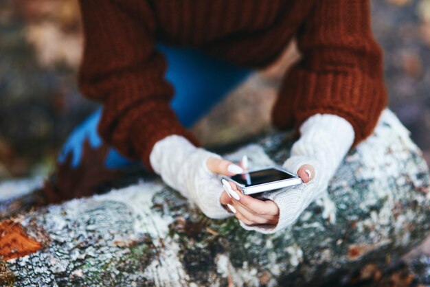 Frauenhände mit Handy im Herbstwald