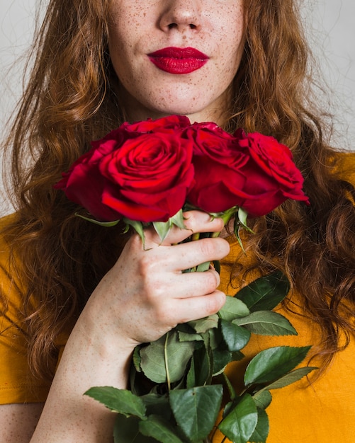 Kostenloses Foto frauenhand, die blumenstrauß von rosen hält