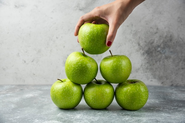 Frauenhand, die einzelnen Apfel von vielen hält.