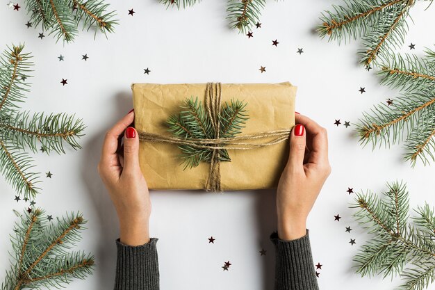 Frauenhand, die Geschenkboxweihnachtsdekorationszusammensetzungstannenbrunch hält
