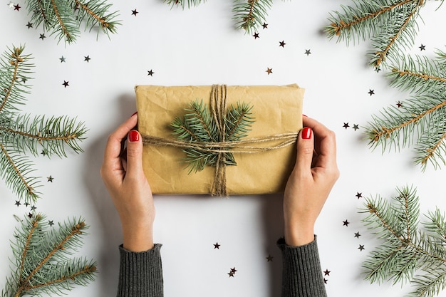 Frauenhand, die Geschenkboxweihnachtsdekorationszusammensetzungstannenbrunch hält