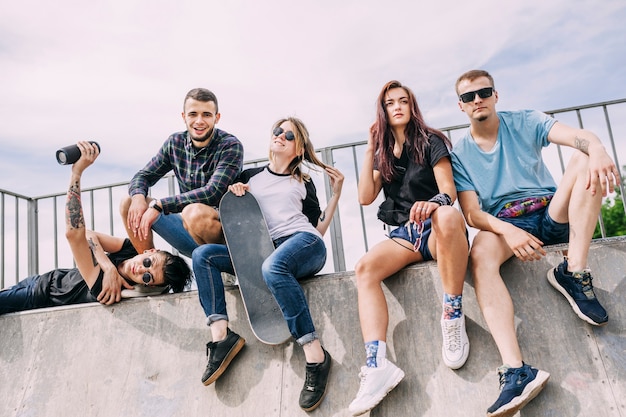 Kostenloses Foto frauenholding-skateboard, das mit freunden auf rampe sitzt