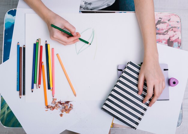 Frauenmalerei auf Papier bei Tisch mit Satz Bleistiften