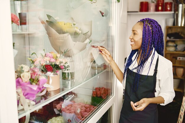 Frauenmanager, der am Arbeitsplatz steht. Dame mit Pflanze in Händen. Glücklicher weiblicher Florist im Blumenmittel-Floristenkonzept.