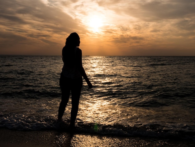 Frauentourist, der den Sonnenuntergang am Meer betrachtet. Entspannung am Meer