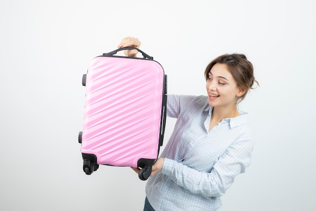 Frauentourist, der rosa Reisekoffer steht und hält. Foto in hoher Qualität