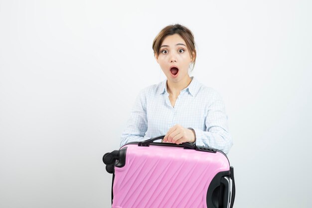 Frauentourist, der rosa Reisekoffer steht und hält. Foto in hoher Qualität
