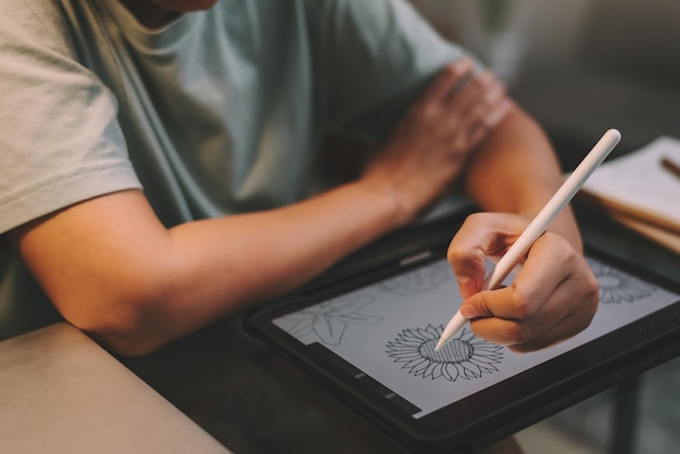 Freiberuflerin der asiatischen Grafikdesignerin, die nachts Überstunden macht, indem sie ein Tablet zum Zeichnen von Kunstwerken von zu Hause aus verwendet