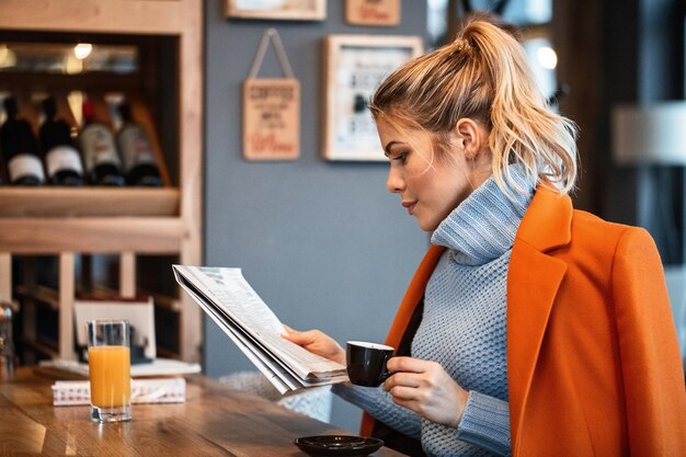 Freiberuflerin entspannt sich in der Kaffeepause und liest Zeitung in der Cafeteria