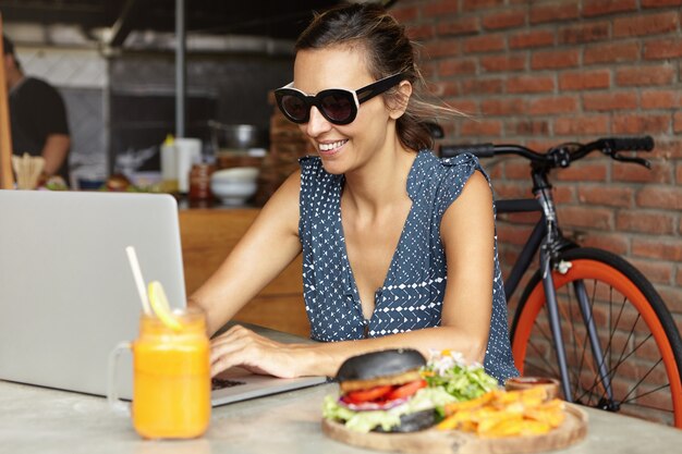 Freiberuflerin in stilvoller Sonnenbrille mit Laptop-PC für Fernarbeit