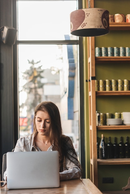 Freiberuflich tätige Frau, die mit Laptop in der Kaffeestube arbeitet