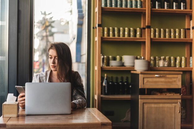 Freiberuflich tätige Frau, die mit Laptop in der Kaffeestube arbeitet