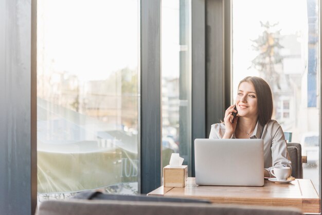 Freiberuflich tätige Frau, die mit Laptop in der Kaffeestube arbeitet