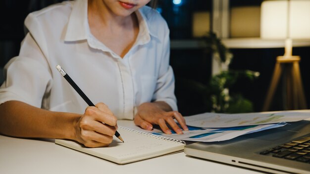 Freiberufliche Asia-Dame mit Laptop-Hartarbeit im Wohnzimmer im Haus.