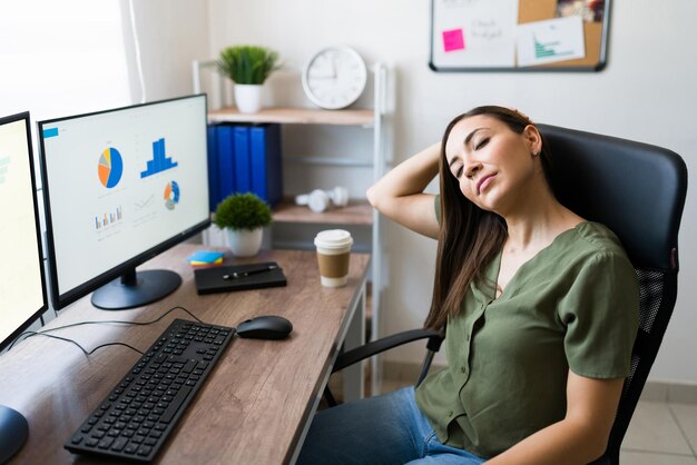 Freiberufliche Frau und Handelsvertreterin, die unter Nackenschmerzen leidet, weil sie viel Zeit damit verbracht hat, vor dem Computer zu sitzen und zu arbeiten