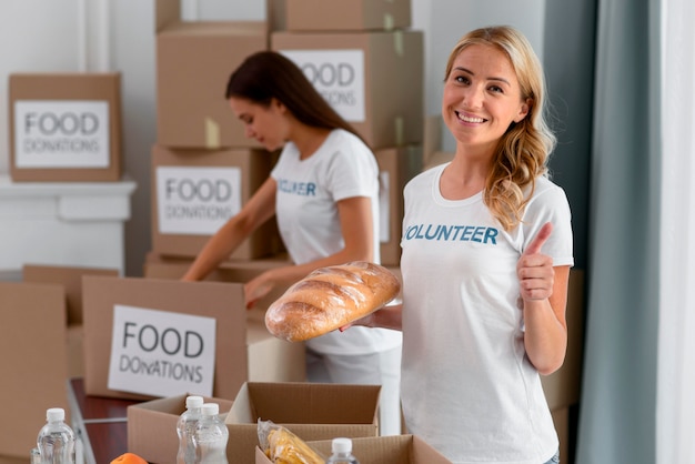 Freiwillige Helferin hilft bei Lebensmittelspenden und gibt Daumen hoch