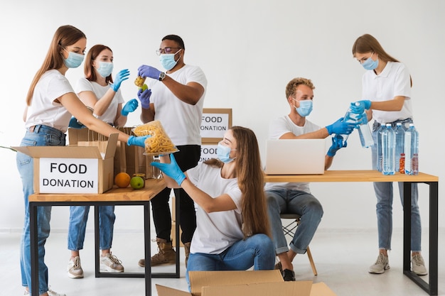 Kostenloses Foto freiwillige mit medizinischen masken bereiten spendenboxen mit proviant vor