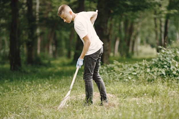 Freiwilliger Teenager. Europäischer Junge in Handschuhen, der Plastikflaschen in einen schwarzen Müllsack im Freien aufhebt.