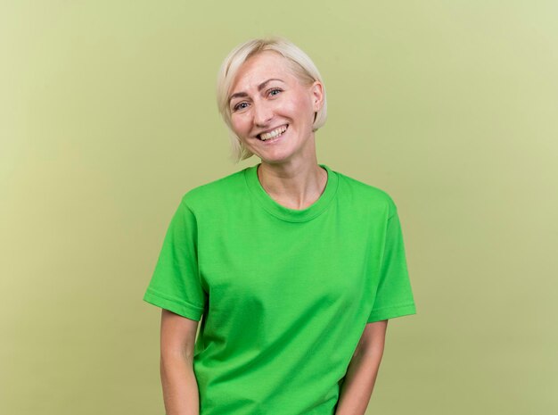 Freudige blonde slawische Frau mittleren Alters, die Front lächelnd lokalisiert auf olivgrüner Wand mit Kopienraum betrachtet