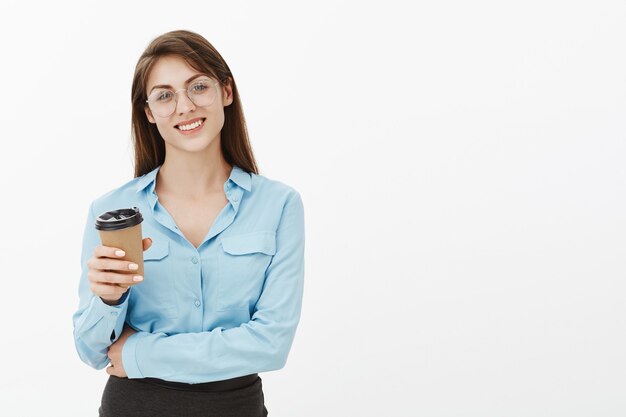 Freudige brünette Geschäftsfrau, die im Studio mit Kaffee aufwirft