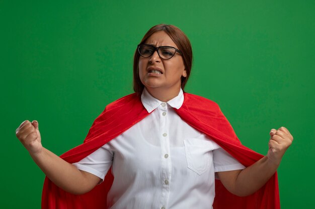 Freudige Superheldenfrau mittleren Alters, die eine Brille trägt, die auf grün isolierte Ja-Geste zeigt