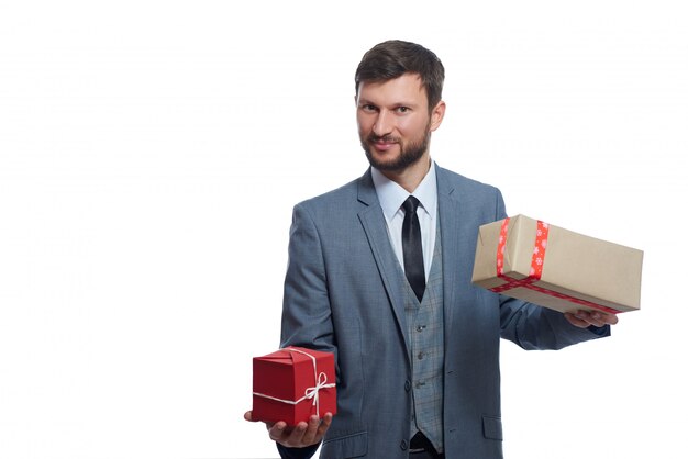 freudiger bärtiger Geschäftsmann, der zwei Geschenkboxen hält, um lächelnd auf Weiß zu wählen