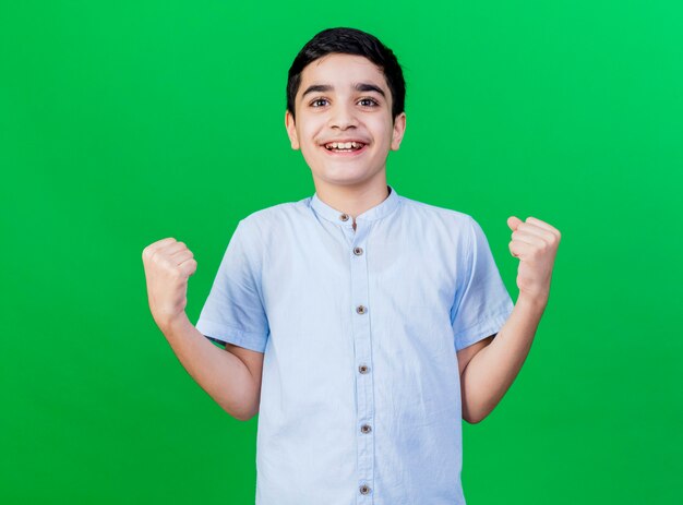 Freudiger junger kaukasischer Junge, der ja Geste lokalisiert auf grüner Wand tut