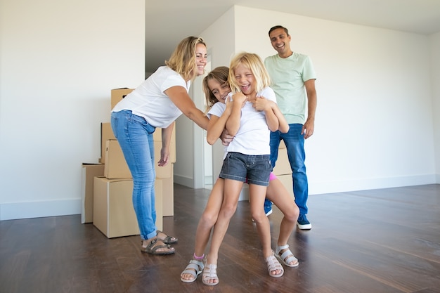 Freudiges Familienpaar und zwei Kinder, die Spaß beim Umzug in die neue Wohnung haben