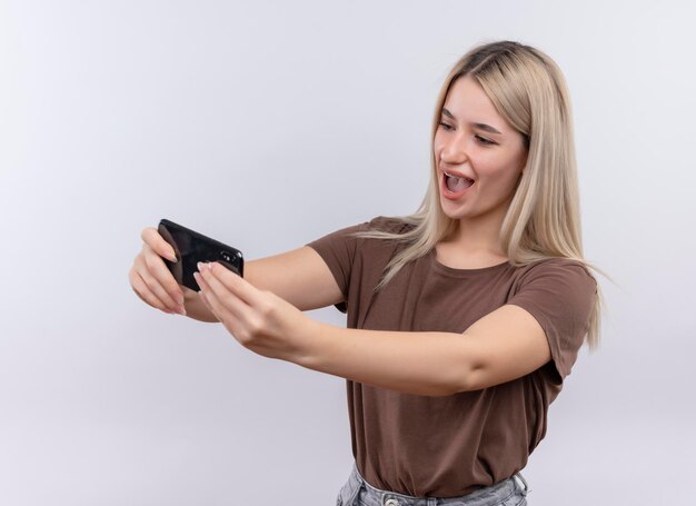 Freudiges junges blondes Mädchen in Zahnspangen, die selfie auf lokalisiertem Leerraum nehmen